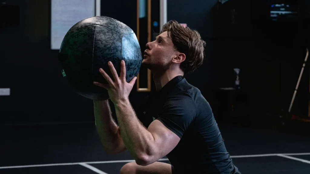 Personal trainer performing a controlled medicine ball exercise as part of a strength and conditioning session