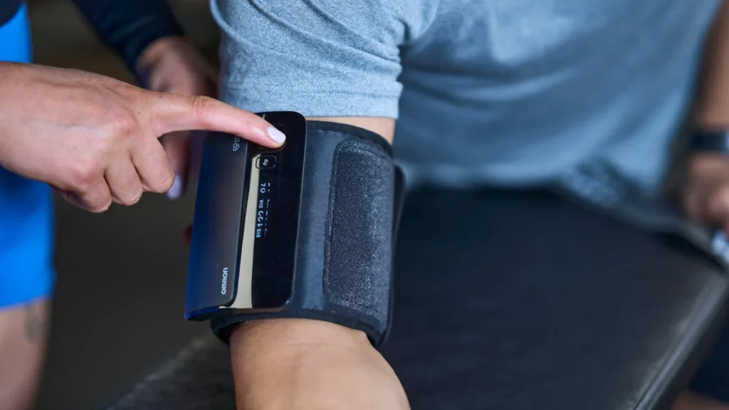 Clinical exercise specialist measuring a client’s blood pressure using an upper-arm monitor before exercise